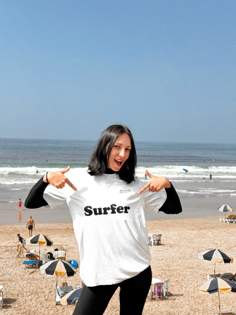 Happy surf student in a Berber Break Surfer t-shirt on the beach